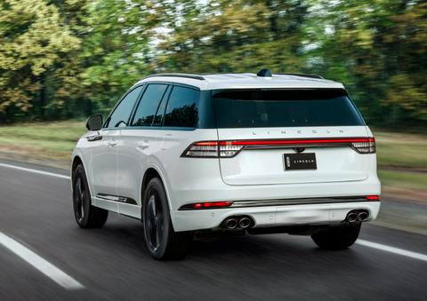 A white 2025 Lincoln Aviator® SUV is being driven away down a road lined with colorful trees. | Sedano Lincoln in La Mesa CA