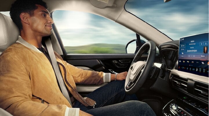 A person is shown using Lincoln BlueCruise hands-free highway driving technology on a divided highway called a Hands-Free Blue Zone. | Sedano Lincoln in La Mesa CA