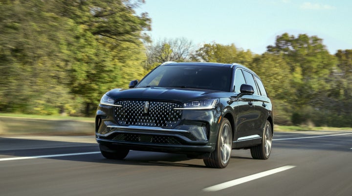 A 2026 Lincoln Black Label™ Aviator® SUV is being driven down a road lined with trees. | Sedano Lincoln in La Mesa CA