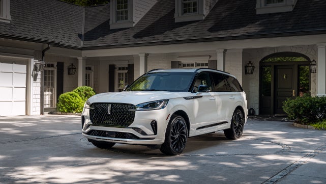 A white 2026 Lincoln Aviator® SUV is parked in the driveway of a luxury home. | Sedano Lincoln in La Mesa CA