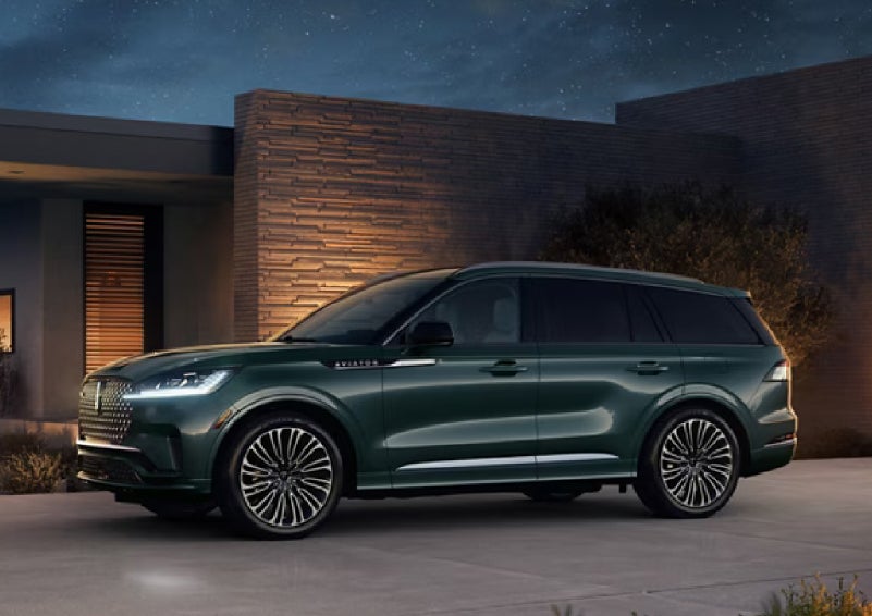 A green 2027 Lincoln Aviator® SUV is parked outside a contemporary home. | Sedano Lincoln in La Mesa CA