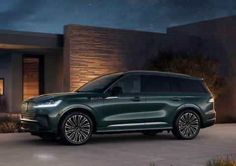 A green 2027 Lincoln Aviator® SUV is parked outside a contemporary home. | Sedano Lincoln in La Mesa CA