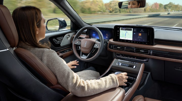 A 2027 Lincoln Aviator® SUV is being driven hands-free on a highway lined with trees. | Sedano Lincoln in La Mesa CA