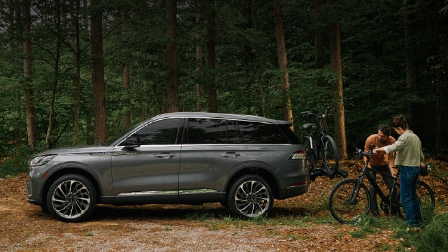 A father and son load e-bikes on a bike rack attached to a 2027 Lincoln Aviator® SUV. | Sedano Lincoln in La Mesa CA
